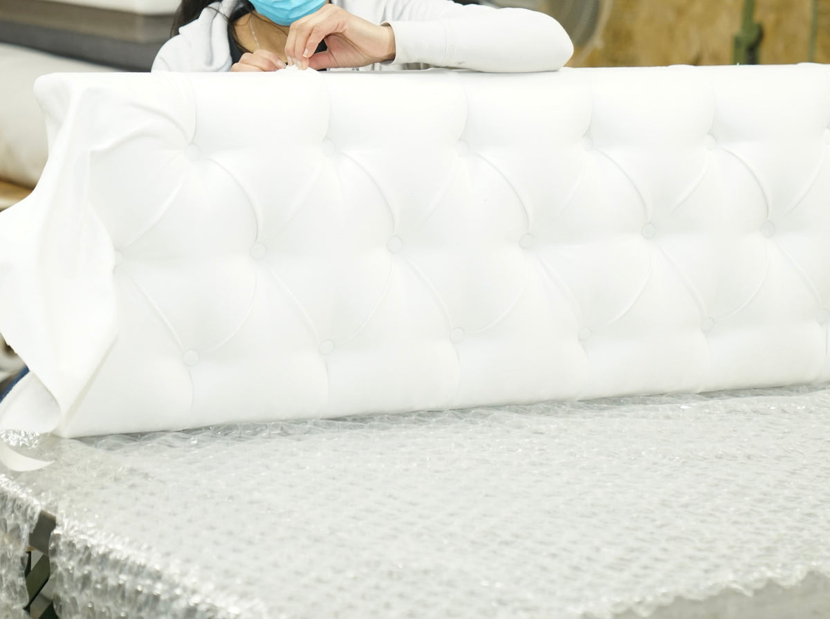 An upholstered, button-tufted headboard being worked on by hand